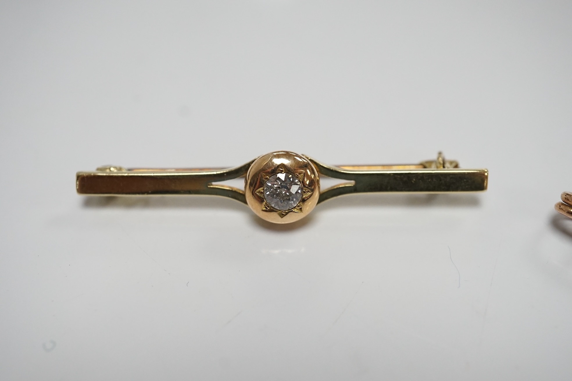 An early 20th century 15ct and solitaire diamond set bar brooch, 44mm, gross 3.5 grams and a similar 15ct, ruby and seed pearl set ribbon bow bar brooch, 2.4 grams. Condition - fair to good